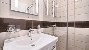 A modern bathroom with a white sink, a glass shower enclosure, and a mirror above the sink. - PANORAMIC APARTMENT WITH SEE VIEW (Podstrana)