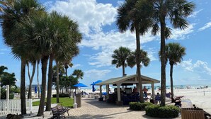 A paved walkway lined with palm trees and benches, leading to a beach area with umbrellas and a gazebo. - Siesta Key Resort, Private beach, pickle ball & tennis paradise. (Siesta Key)