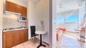 Cuina compacta amb armaris de fusta, microones i un respatller de rajola.