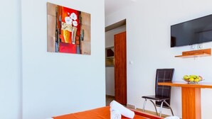 A hotel room with a bed, a desk, a chair, a television, and a painting on the wall. - ROOM WITH SEE VIEW FOR 2 (Podstrana)
