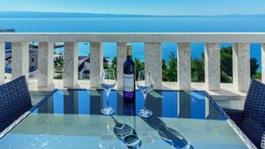 A table with a bottle of wine and two glasses on a balcony overlooking a body of water. - ROOM WITH SEE VIEW FOR 2 (Podstrana)