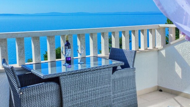 A balcony with a glass table and wicker chairs, overlooking a clear blue sea. - ROOM WITH SEE VIEW FOR 2 (Podstrana)