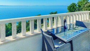 A balcony with a glass table and wicker chairs overlooking a clear blue sea. - ROOM WITH SEE VIEW FOR 2 (Podstrana)