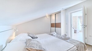 Een slaapkamer met twee bedden, een groot raam en een deur naar een buitenruimte.