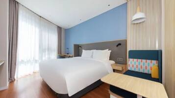 Quarto de hotel com uma cama grande, uma mesinha de cabeceira, uma cadeira e uma janela com cortinas.