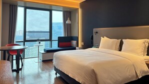 Una habitación de hotel con una cama grande, un escritorio y vistas a la ciudad.