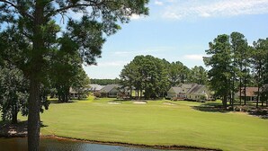 Un parcours de golf avec un étang, entouré de maisons résidentielles.