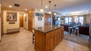A spacious kitchen with wooden cabinets, a granite countertop, pendant lighting, and a dining area with a table and chairs. - Large 3 Bedroom Bathroom In Mountaineer Square Condo - No Cleaning Fee! by RedAwning (Crested Butte)