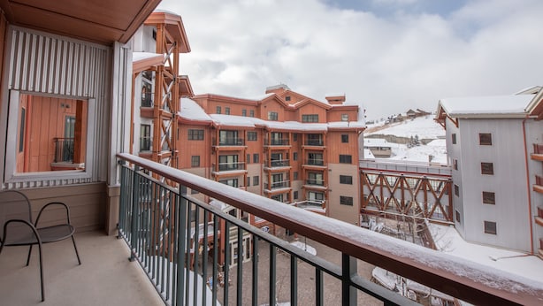 A balcony with a view of multi-story buildings, a wooden railing, and a snow-covered ground. - Large 3 Bedroom Bathroom In Mountaineer Square Condo - No Cleaning Fee! by RedAwning (Crested Butte)
