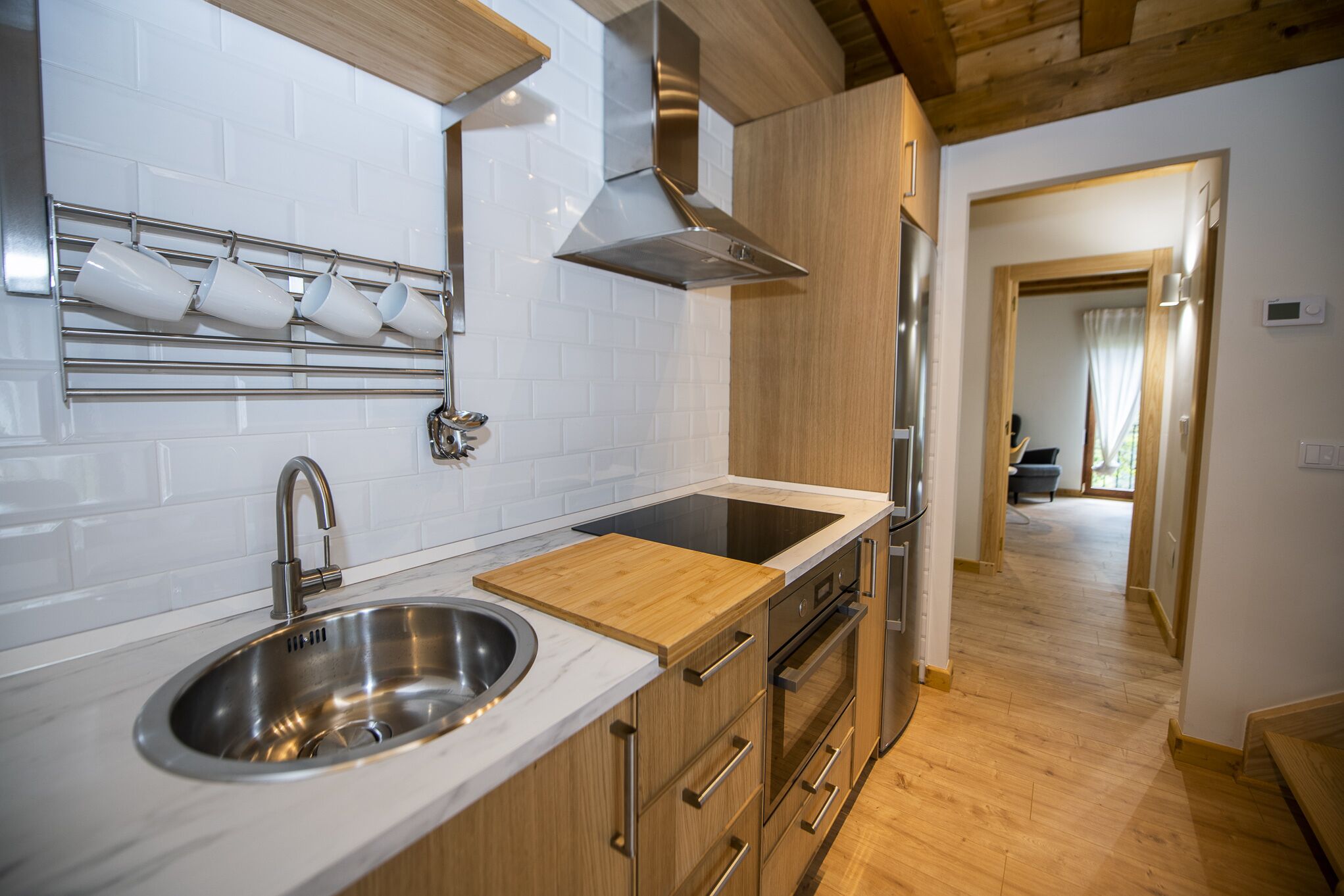 A modern kitchen with a stainless steel sink, wooden cabinets, and a stainless steel range hood.