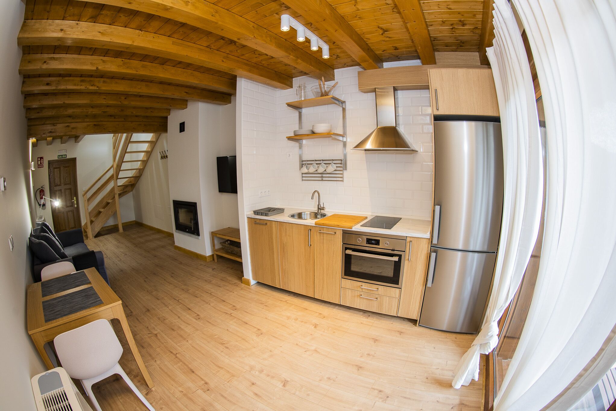 A compact kitchen with wooden cabinets, a stainless steel refrigerator, and a small countertop.