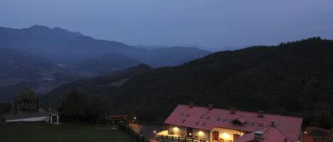 Un refugio de montaña con techo rojo, paredes de piedra y un camino de entrada pavimentado.