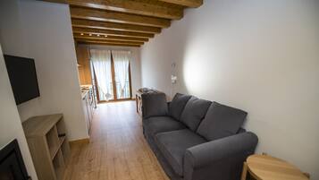 A living room with a grey sofa, a wooden coffee table, and a TV mounted on the wall.