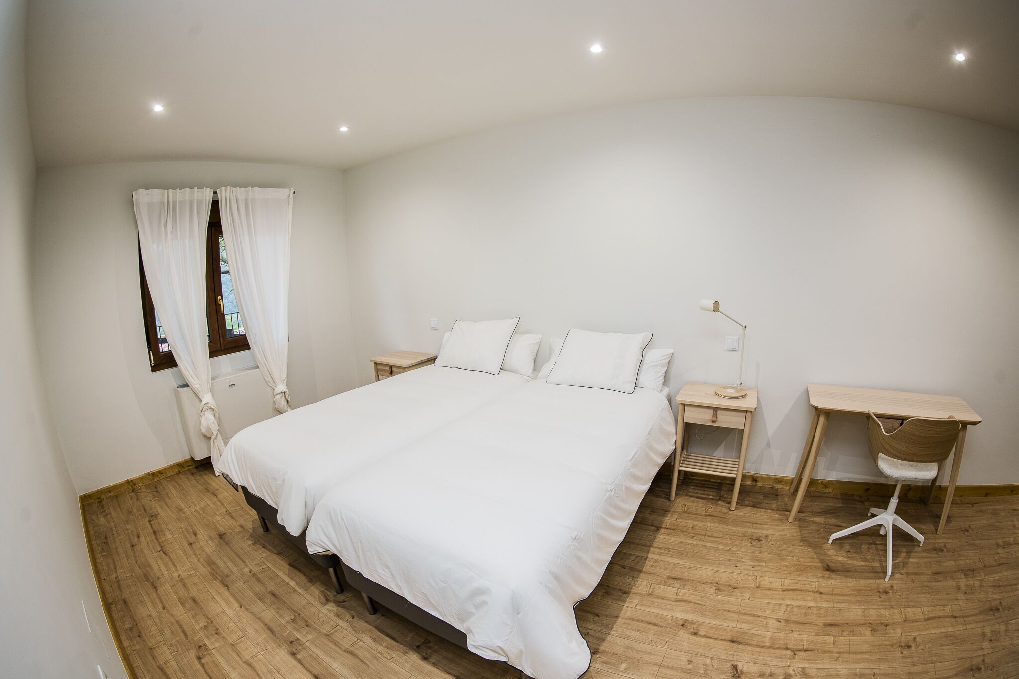 A bedroom with a large bed, a desk, and a chair.