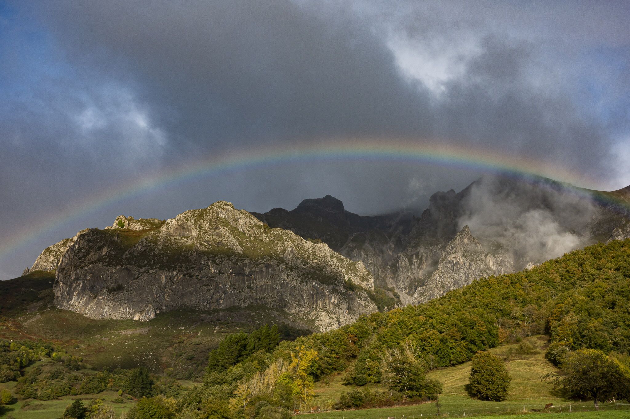 A mountainous landscape with a prominent rocky peak and a lush green valley.