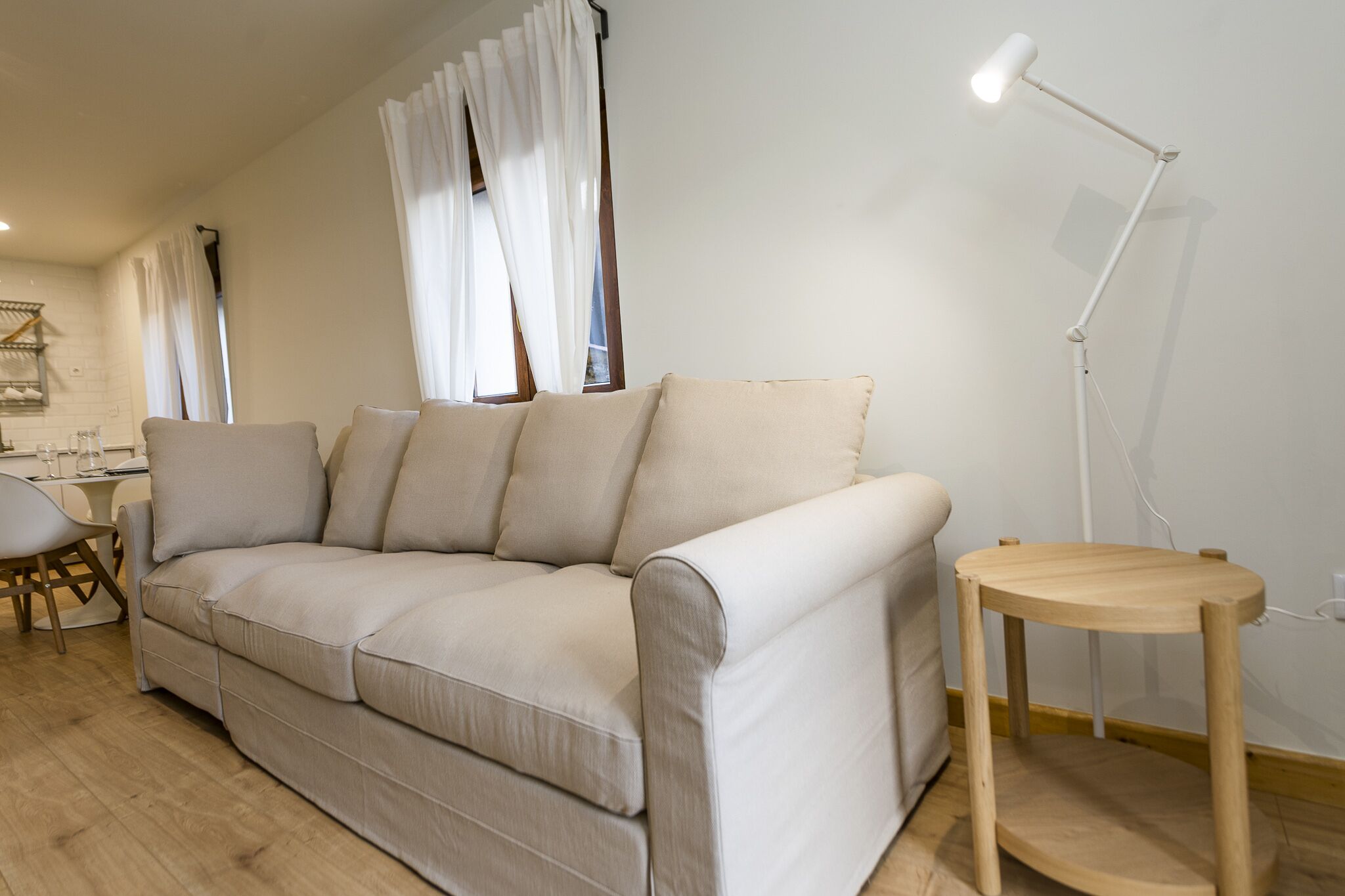 A modern living room with a beige sofa, a wooden side table, and a floor lamp.