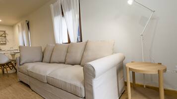 A modern living room with a beige sofa, a wooden side table, and a floor lamp.