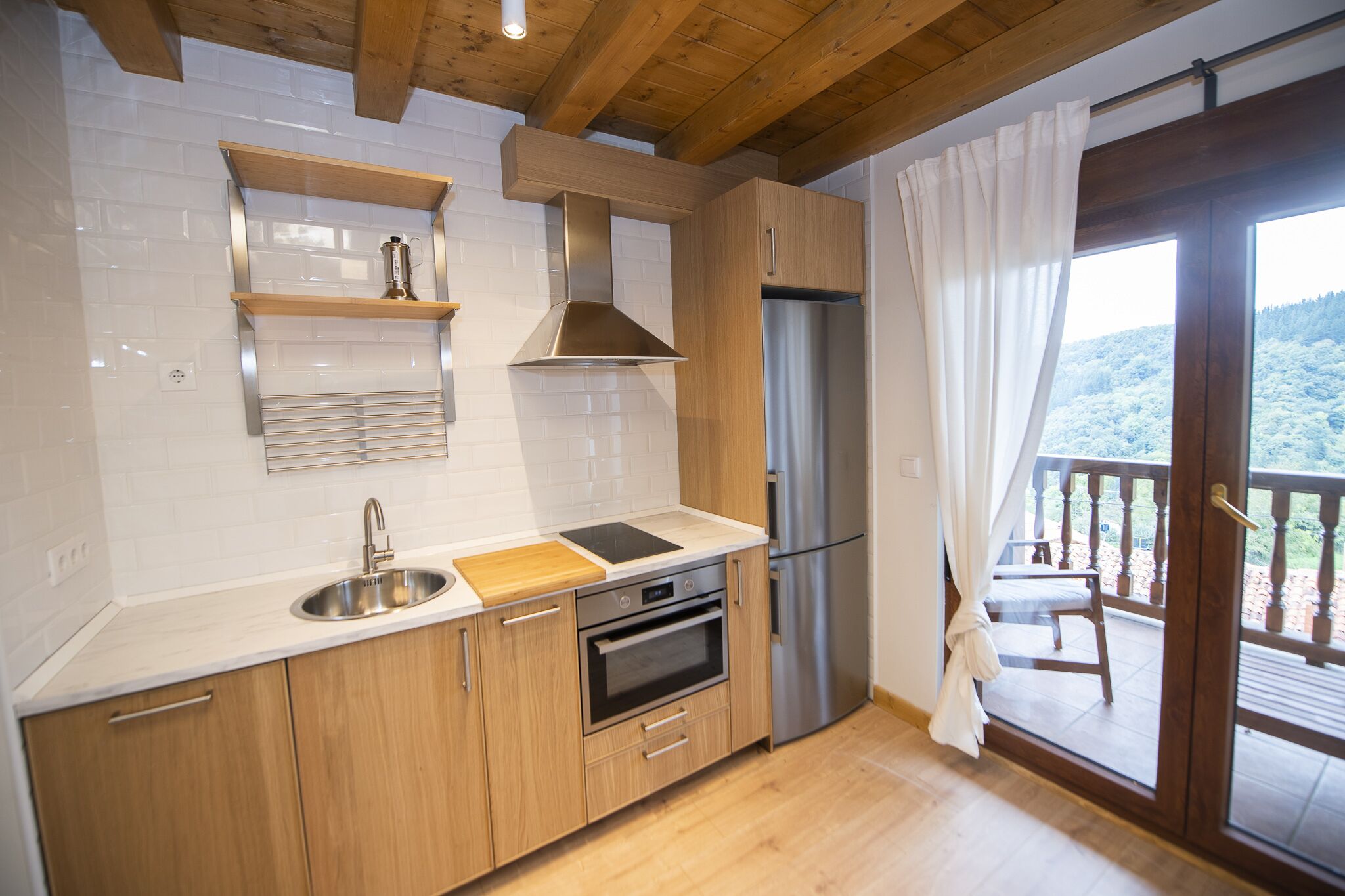Una cocina moderna con armarios de madera, un lavamanos de acero inoxidable y un horno empotrado.