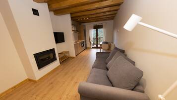 Un soggiorno moderno con soffitto in legno, un divano grigio, un camino e un'area pranzo con tavolo e sedie.