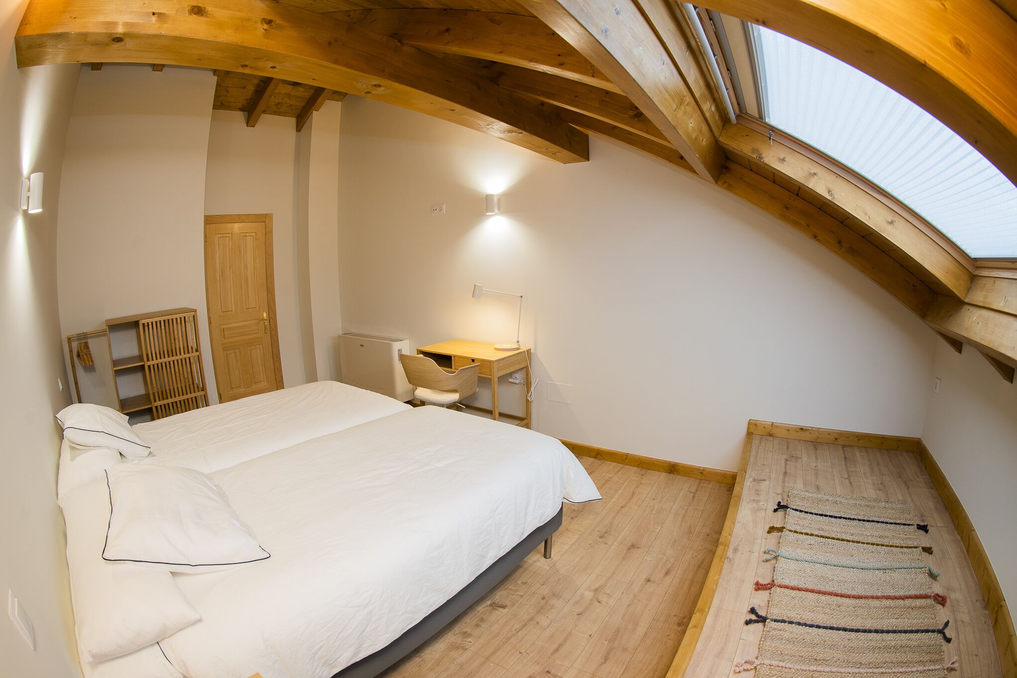 Ein Schlafzimmer mit Bett, Schreibtisch und Fenster.