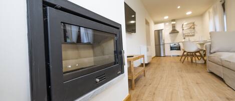 Una sala moderna con chimenea empotrada, piso de madera, un sofá y un comedor al fondo.