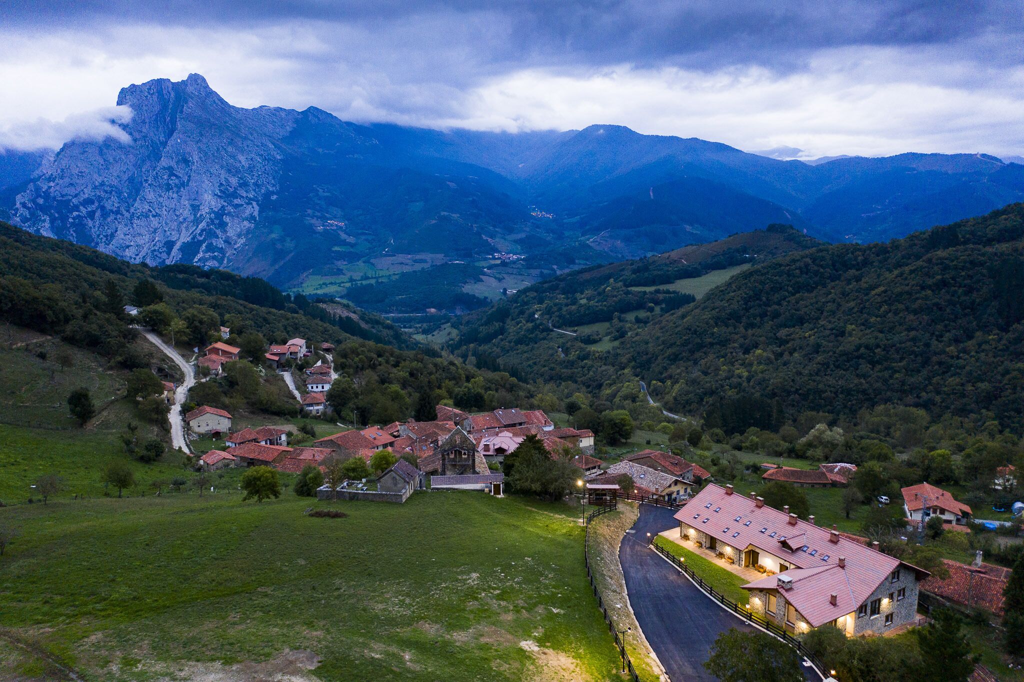 A village with traditional architecture, surrounded by mountains and greenery.