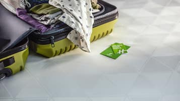 A suitcase with a green and yellow exterior, partially open, revealing clothes and a white patterned cloth inside.