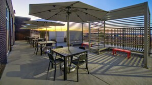 An outdoor patio with tables, chairs, and umbrellas. - Holiday Inn Erie by IHG (Erie)