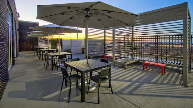 An outdoor patio with tables, chairs, and umbrellas.