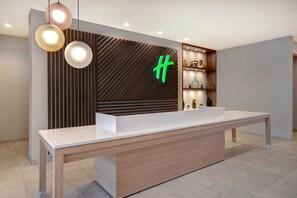 A reception desk with a modern design, featuring a wooden finish and a white countertop. - Holiday Inn Erie by IHG (Erie)