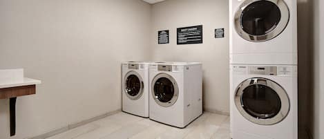 A laundry room with two front-loading washing machines and a sink.
