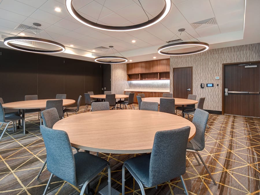 A conference room with round tables and chairs, a patterned carpet, and modern lighting fixtures.