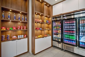 Un espace dédié aux collations et aux boissons, avec des étagères en bois et des présentoirs réfrigérés.
