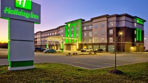 A Holiday Inn hotel with a prominent sign, multiple parking spaces, and a well-lit entrance.