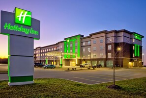 Un hôtel Holiday Inn, reconnaissable à son enseigne bien visible, offrant de nombreuses places de stationnement et doté d’une entrée bien éclairée.