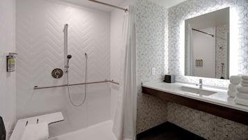 A modern bathroom with a shower, a toilet, a sink, and a mirror.