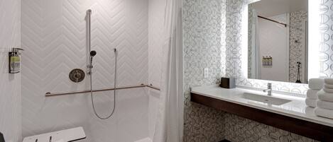 A modern bathroom with a shower, a toilet, a sink, and a mirror.