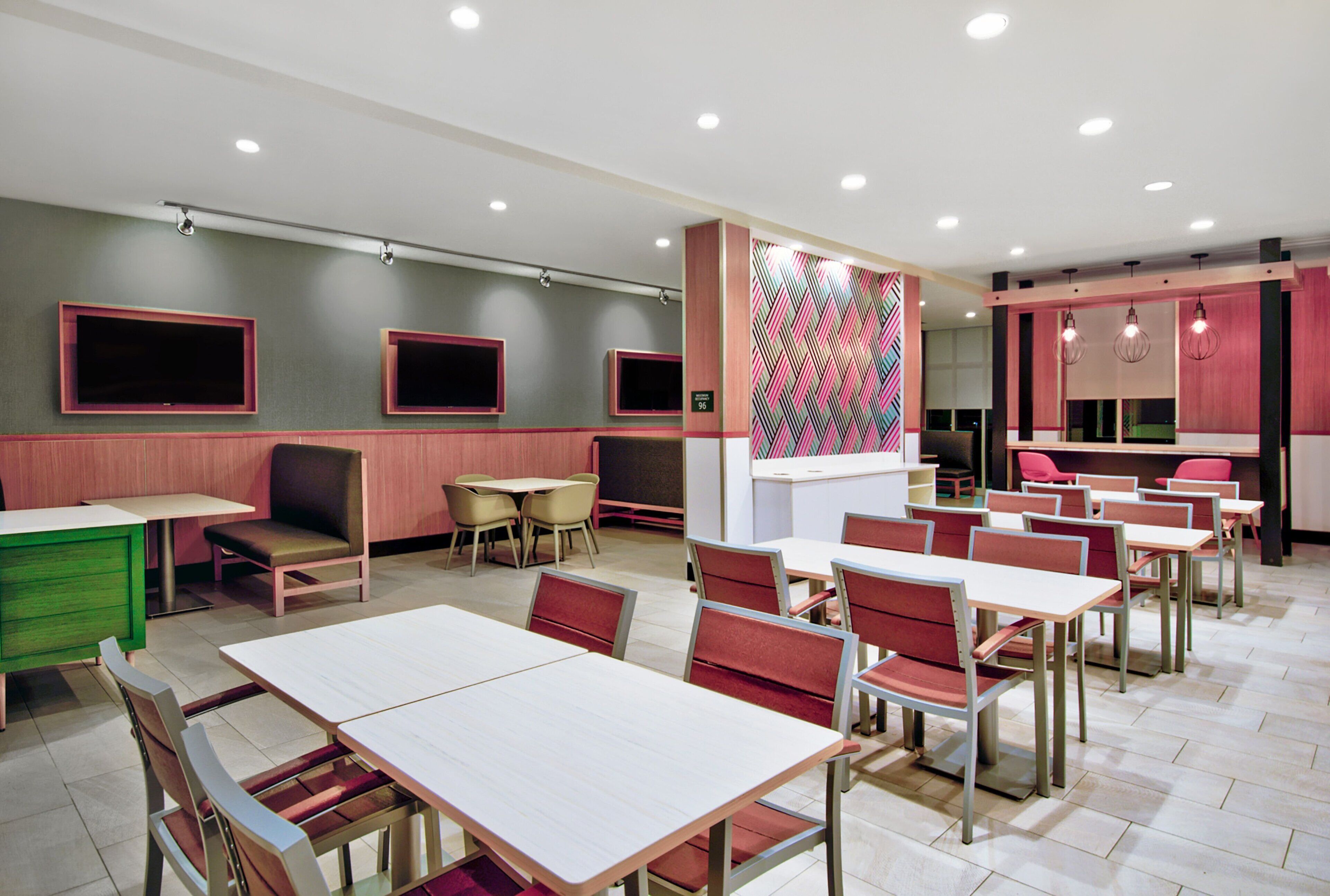 Un comedor moderno con varias mesas y sillas, un armario verde y una pared con estampado.
