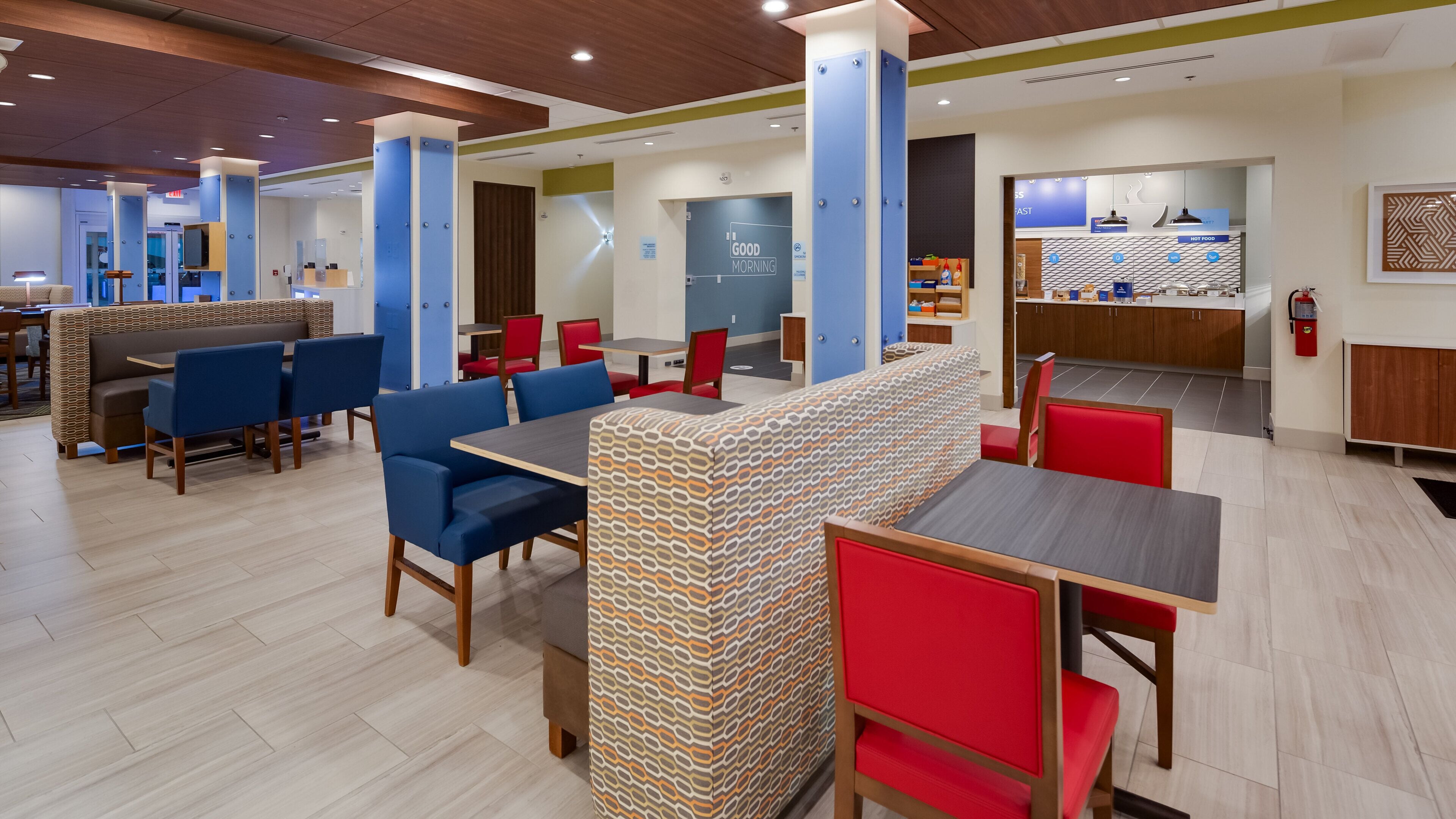 A modern restaurant with booths and tables, a kitchen area, and a sign reading "Good Morning".