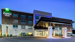 A Holiday Inn Express & Suites building with a modern design, featuring a prominent entrance with a covered walkway and stone pillars.