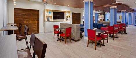 A modern restaurant with wooden floors, red and blue seating, and a wooden ceiling.