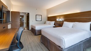 A hotel room with two beds, a desk, a chair, a TV, and a framed picture on the wall.