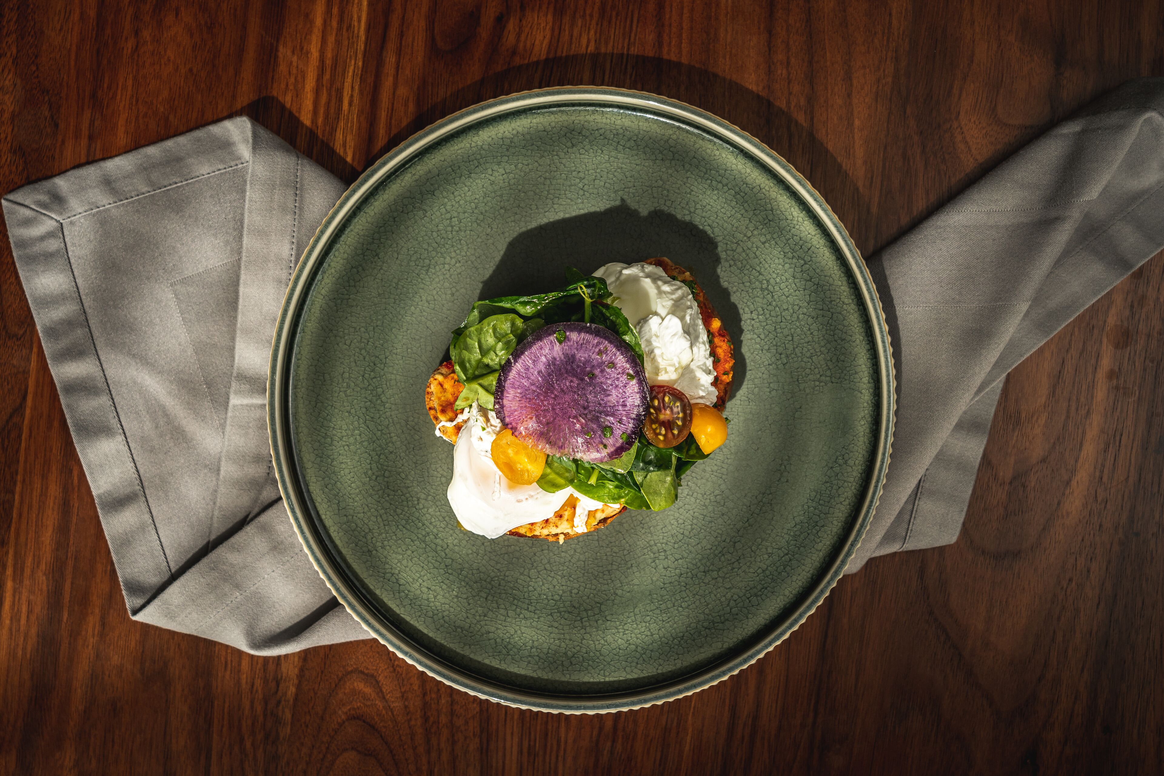 A plate of food on a wooden table with a gray napkin.