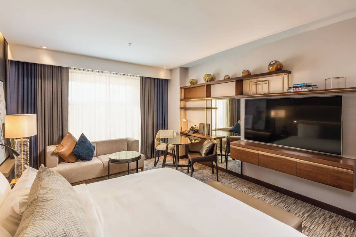 Une chambre d’hôtel avec un grand lit, un bureau, une télévision et un coin salon.
