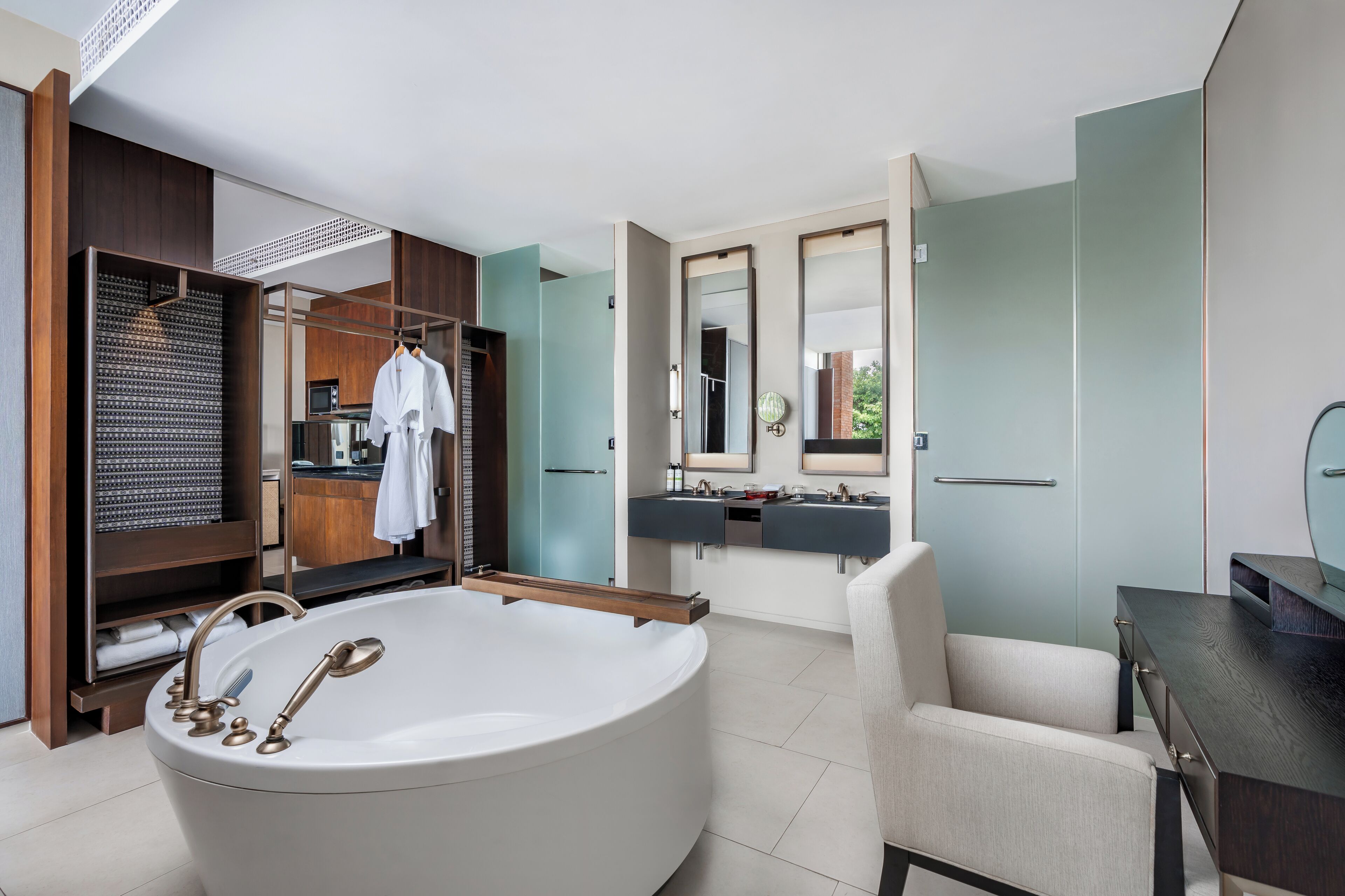 A modern bathroom with a freestanding bathtub, a vanity with two sinks, and a walk-in closet with a hanging rack.