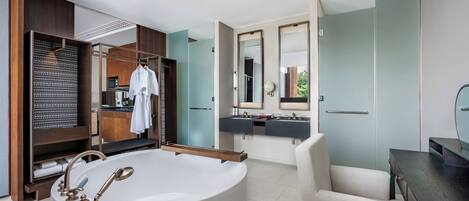 Un baño moderno con una bañera independiente, un tocador doble y un vestidor con perchas.