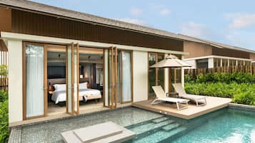 A modern hotel room with a glass door, a pool, and outdoor seating.
