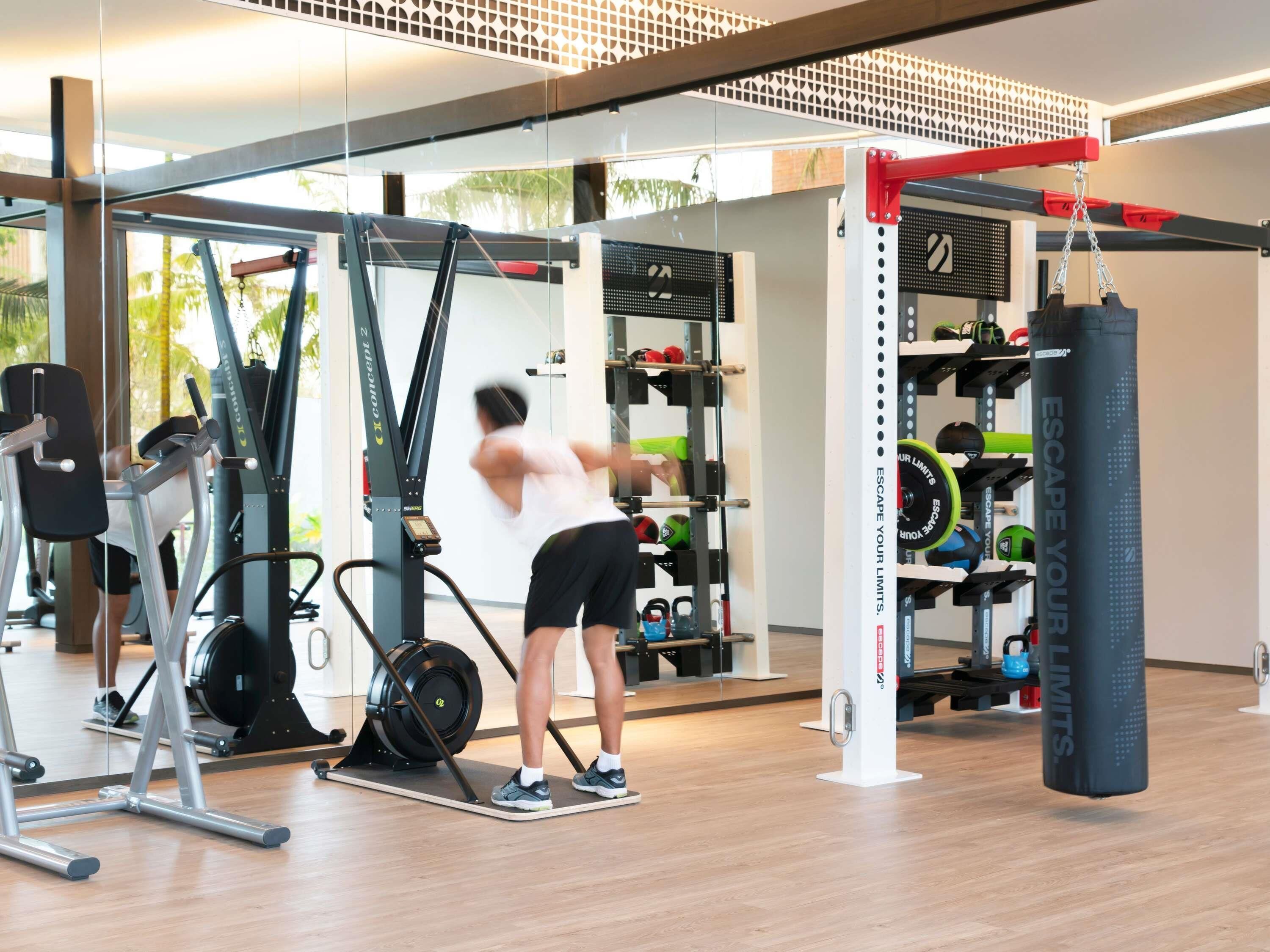 Un gimnasio con equipo de ejercicio, un saco de boxeo y un rack de pesas.