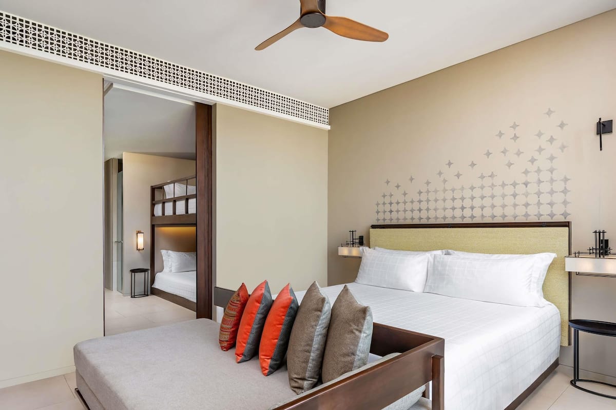 Une chambre d’hôtel avec un lit, une table de chevet, un ventilateur de plafond et un mur décoré d’autocollants en forme d’étoiles.