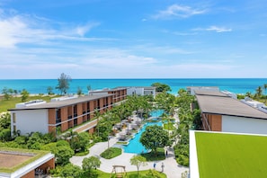 Un resort con piscina central, varias construcciones y vista al océano.